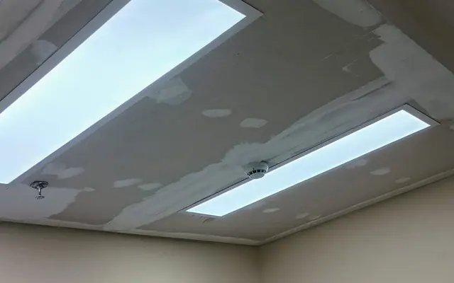 Forro de drywall com luminárias lineares e tratamento de juntas visível