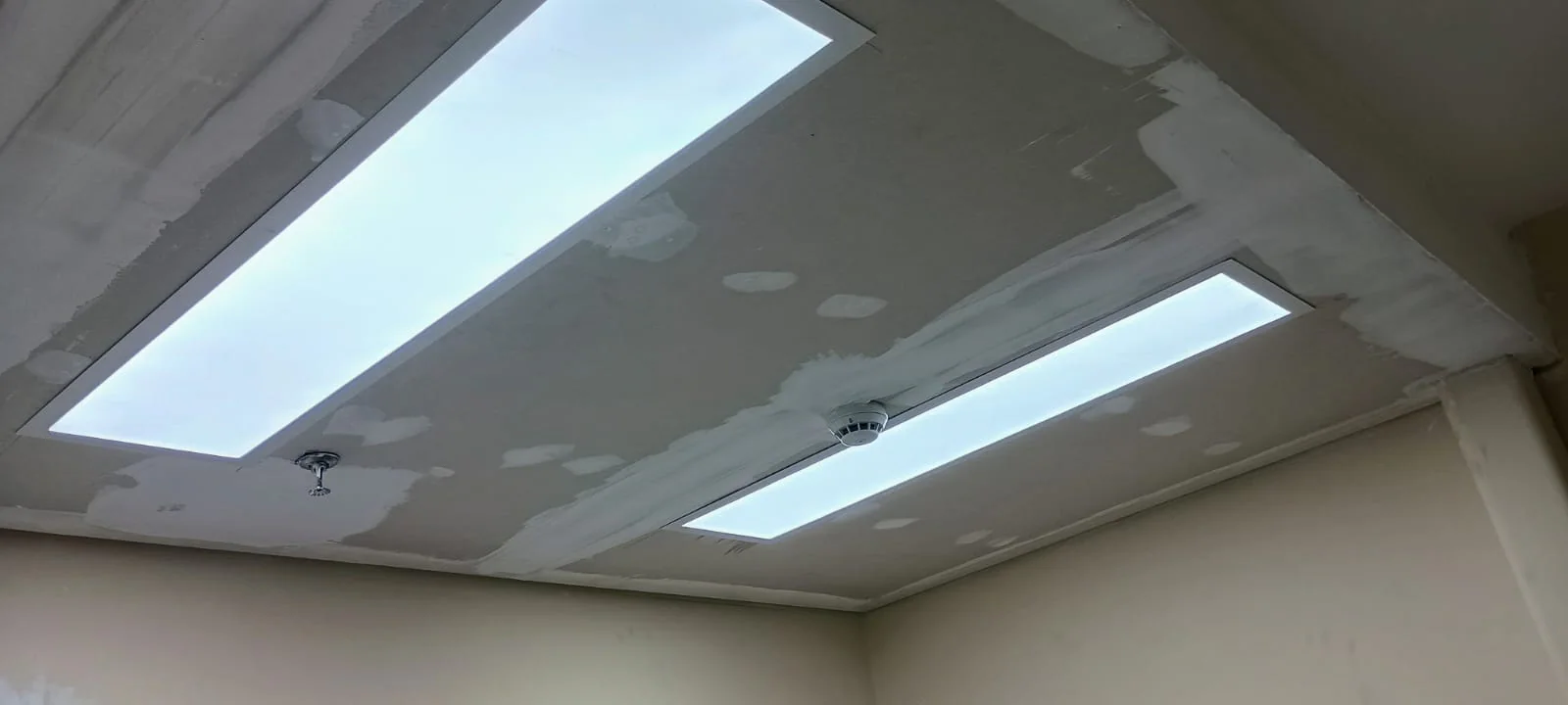 Forro de drywall com recortes para luminárias lineares e juntas em tratamento